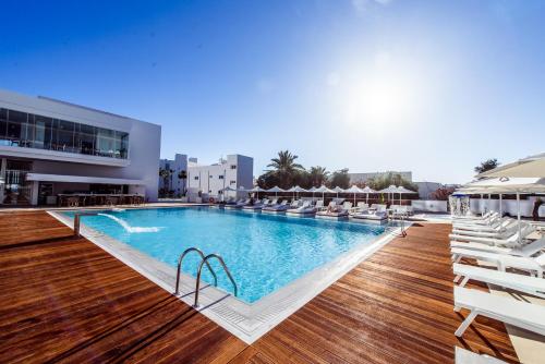 a large swimming pool with chairs and a building at Eleana Hotel in Ayia Napa