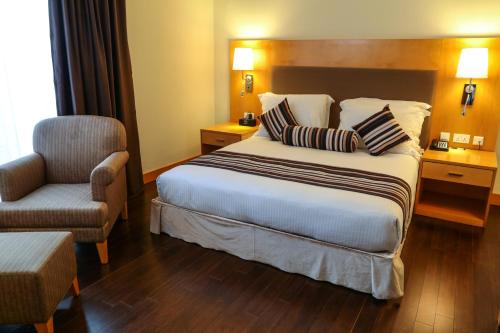 a hotel room with a bed and a chair at Ramada Addis, Addis Ababa in Addis Ababa