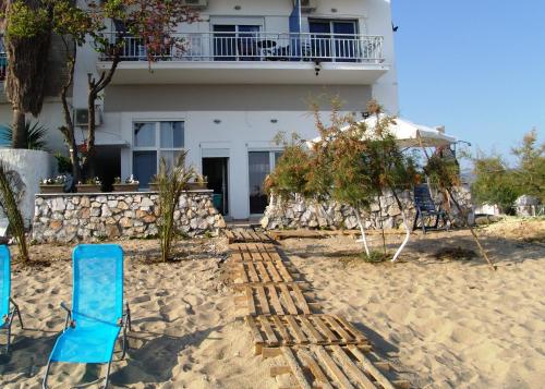 two blue chairs on the beach in front of a building at Dimitra Beach Apartments - Nea Karvali Kavala in Néa Karváli
