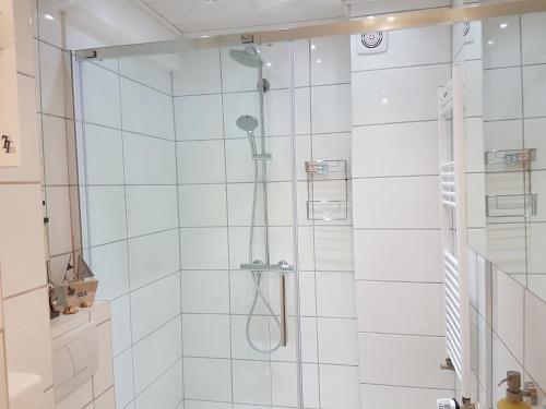 La salle de bains blanche est pourvue d'une douche avec une porte en verre. dans l'établissement Apartment Regina, à Nuremberg