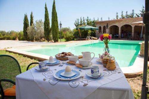 un tavolo con tazze e piatti di cibo accanto a una piscina di Casa Go'El a Chiaramonte Gulfi