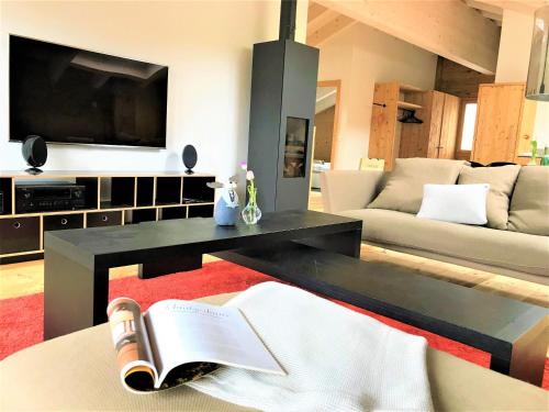 a living room with a couch and a table with a book at Chalet ELK Lenk in Lenk
