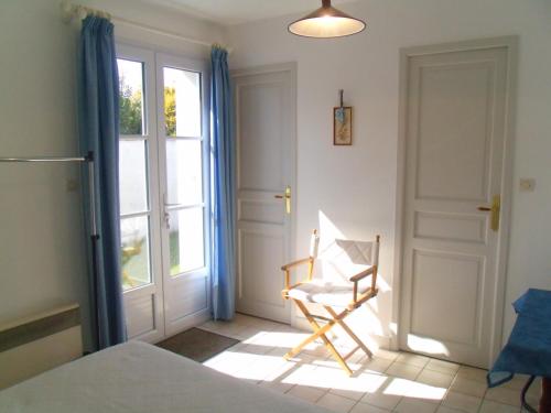 a bedroom with a bed and a chair in front of a door at L'oiseliere in Sainte-Marie-de-Ré