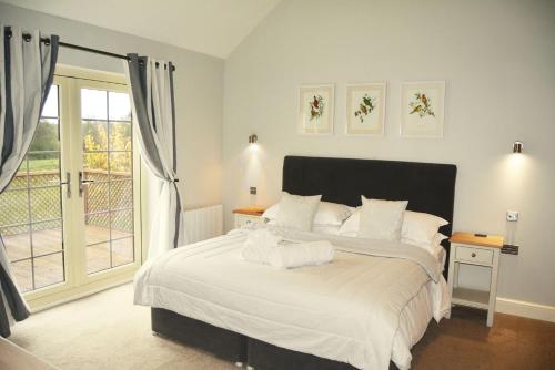 a bedroom with a bed with white sheets and a window at Endymion Lodge in Colchester