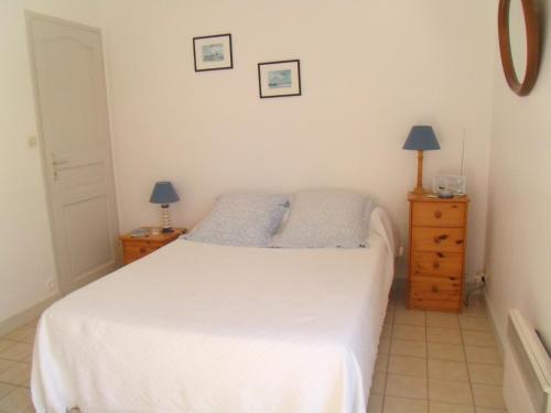a bedroom with a white bed and two night stands at L'oiseliere in Sainte-Marie-de-Ré