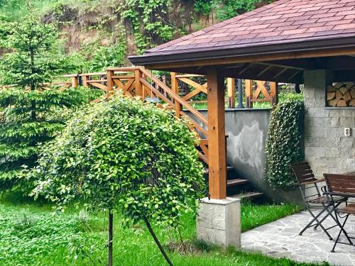 a wooden gazebo with a table and chairs in a yard at Vila Rila Samokov in Samokov