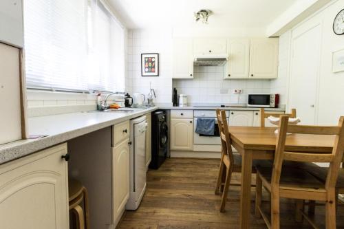 a kitchen with white cabinets and a table and chairs at Modern Central Family-Home for 6 in London