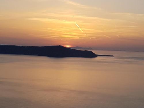 a sunset over a body of water at Adamant Suites in Fira