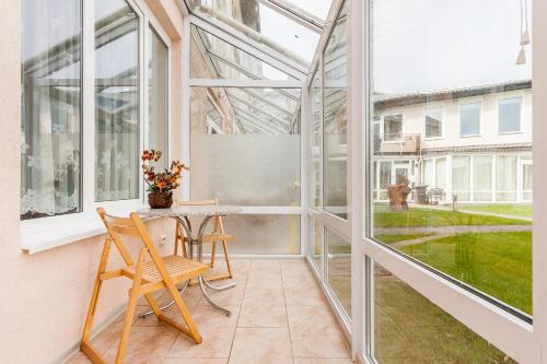 a room with a table and chairs and windows at Prie Ąžuolo in Juodkrantė