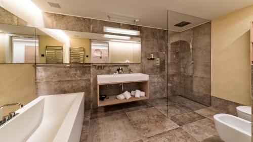 a bathroom with a tub and a sink and a shower at Guesthouse Suiteseven in Merano