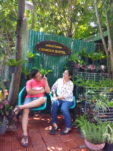 two women sitting on a bench in a garden at Chom Chan Guesthouse & Hostel in Chiang Mai