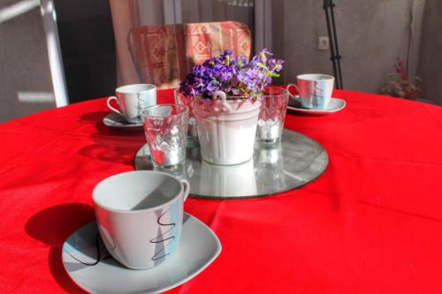 a table with a red table cloth with cups and flowers at Apartments Filip in Podstrana