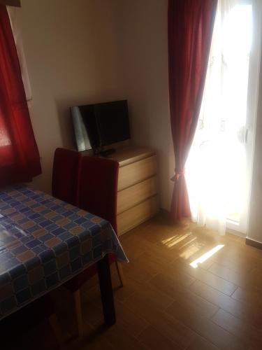 a room with a tv and a table and a window at Apartments Zova in Medulin