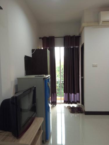 a living room with a tv and a window at Chom Chan Guesthouse & Hostel in Chiang Mai