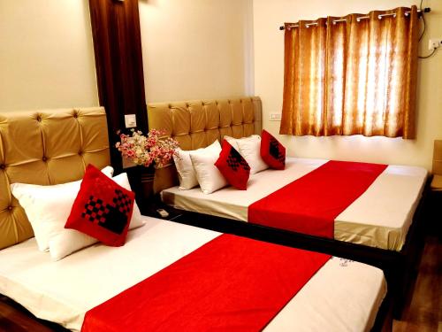 two beds in a room with red and white sheets at City Hotel in Allahābād