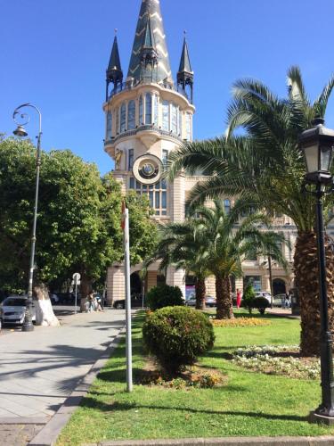un edificio con una torre del reloj con palmeras y luz de la calle en apartamenti drevni batumi, en Batumi