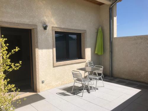 a patio with a table and chairs and a green umbrella at Gites Des Sablons in Châtillon-sur-Marne