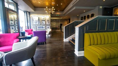 a lobby with a yellow couch and purple chairs at Grey Street Hotel in Newcastle upon Tyne