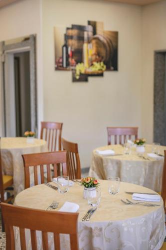 a dining room with two tables with white tableclothsurrencyangering at Hotel del Falco in Cervia