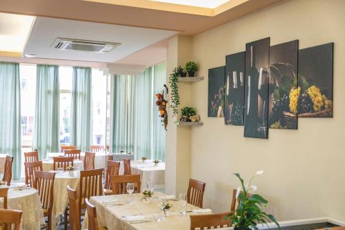 a dining room with tables and chairs and windows at Hotel del Falco in Cervia