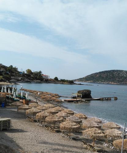 a beach with a bunch of straw umbrellas and the water at me gusta suite by the sea in Anavissos
