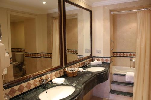 a bathroom with two sinks and a mirror and a tub at Helnan Auberge Fayoum in Fayoum