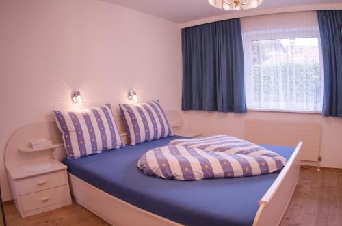 a bedroom with a blue bed with a window at ISIS---Ferienwohnung in Steinach am Brenner