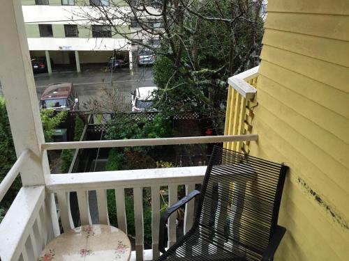 a black bench sitting on a balcony with a view of a street at Barclay House Bed and Breakfast in Vancouver