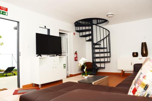 a living room with a spiral staircase and a television at La Casa de la Abuela in Ponta do Sol