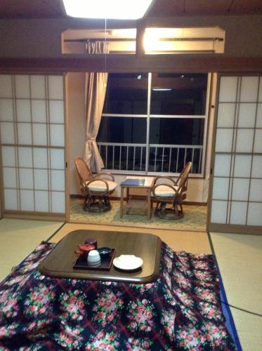 a living room with a table on a rug at Kadowakikan in Nozawa Onsen