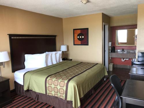 Habitación de hotel con cama y escritorio en Days Inn by Wyndham Corpus Christi Beach, en Corpus Christi