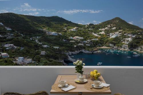 a table with two cups of coffee and fruit on a balcony at Maridea Casa Vacanza- Le Alcove sul Mare Suites in Ponza