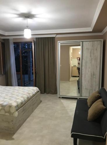 a bedroom with a bed and a couch and a mirror at 15 Kviparosi Guest House in Makhinjauri