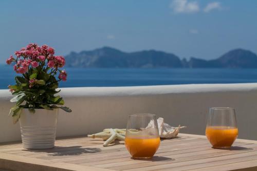 two glasses of orange juice and a vase of flowers on a table at Maridea Casa Vacanza- Le Alcove sul Mare Suites in Ponza
