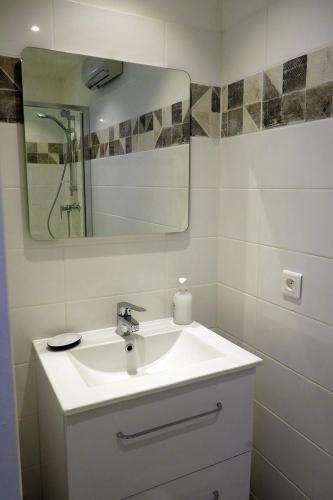 une salle de bain blanche avec un lavabo et un miroir dans l'établissement Envies en Lubéron, à Saignon