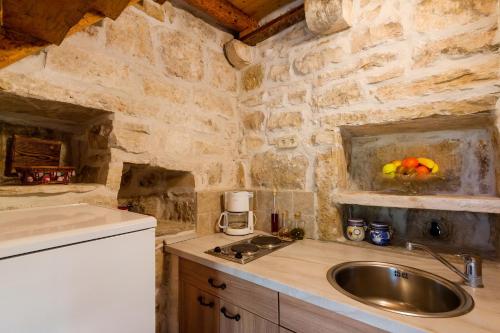 a kitchen with a sink and a stone wall at Old Small Stone House in Korčula