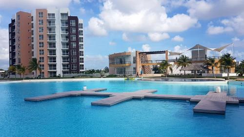 a large swimming pool with benches in front of buildings at Departamento en Dream Lagoons Cancun in Cancún