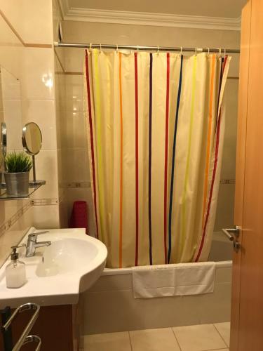 a bathroom with a sink and a shower curtain at Apartamento Porto de Areia in Peniche