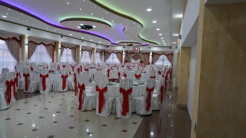 a banquet hall with white tables and white chairs at Meka Hotel in Dragash