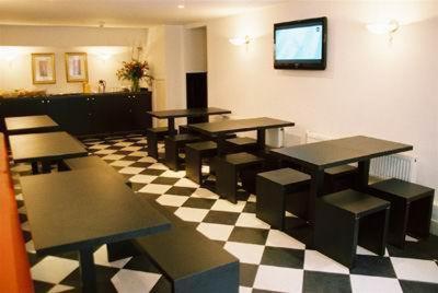 a restaurant with tables and chairs and a tv on the wall at Hotel 74 in Amsterdam