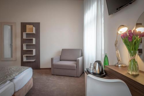 a bedroom with a bed and a chair and a desk at Pytloun Kampa Garden Hotel Prague in Prague