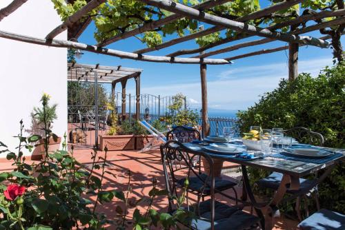 Una mesa y sillas en un patio con vista al mar. en Residence Gioia, en Furore