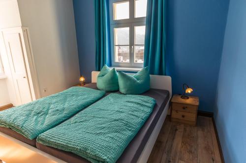 a bedroom with a bed with blue walls and a window at Ferienwohnungen Endler in Bad Schandau