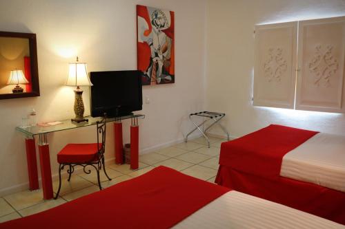 a room with two beds and a desk with a television at Zar Los Mochis in Los Mochis