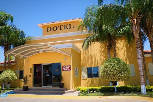 a hotel with palm trees in front of a building at Zar Los Mochis in Los Mochis