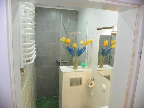 a bathroom with a shower with vases of yellow flowers at Dom Goscinny Andy in Pobierowo