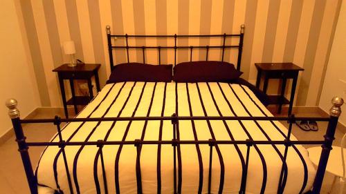 a bed with a black metal frame and two night stands at Casa Duomo in Aversa