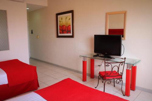 a room with a desk with a television and a bed at Zar Culiacan in Culiacán