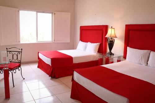 Habitación de hotel con 2 camas con colchas rojas en Zar Culiacan, en Culiacán