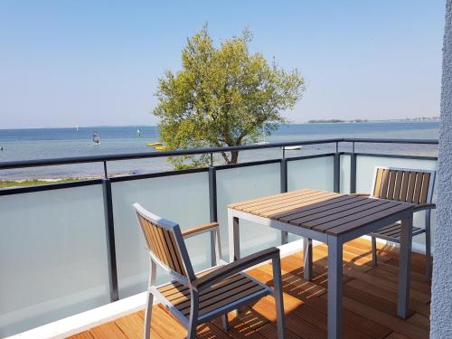 a table and chairs on a balcony with a view of the water at Haus Achtern Diek in erster Reihe am Meer in Fehmarn